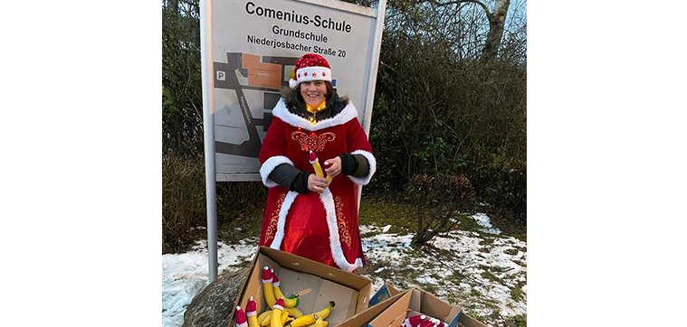 Nikoletta vor dem Schild der Comenius Schule mit Bananen