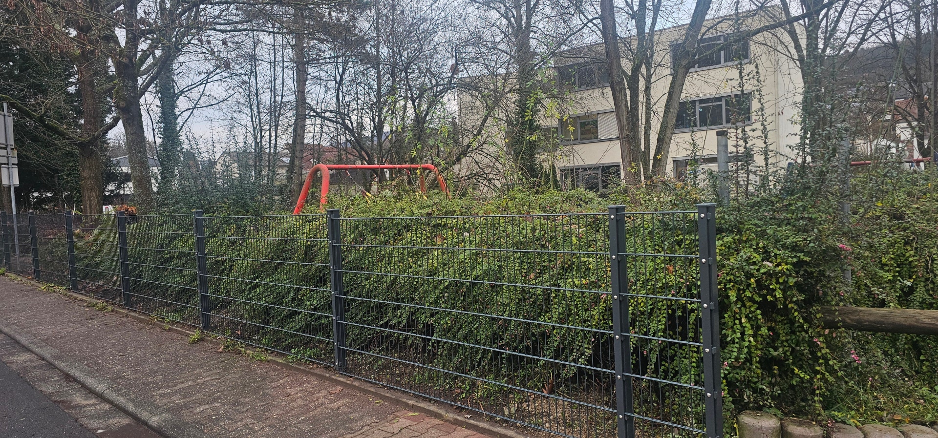 Foto: Der neue Zaun entlang der Straße Am Bündelberg, im Hintergrund ist das Rathaus zu sehen. 