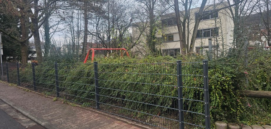 Foto: Der neue Zaun entlang der Straße Am Bündelberg, im Hintergrund ist das Rathaus zu sehen. 