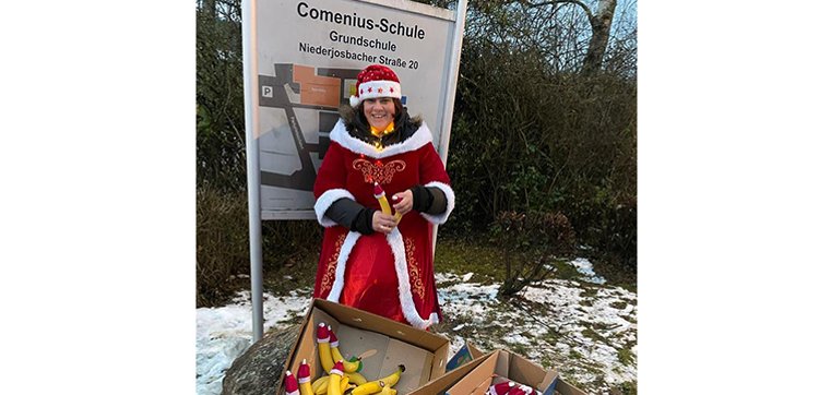 Nikoletta vor dem Schild der Comenius Schule mit Bananen